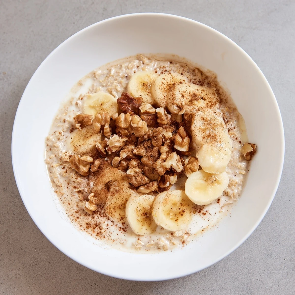 Steaming warm chai oat with banana slices and toasted nuts, a comforting breakfast.