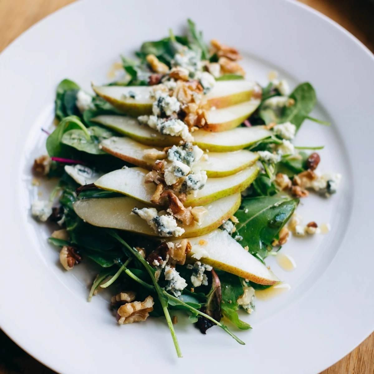 A close-up of a colorful Winter Pear Greens salad, garnished with toasted pecans and blue cheese.