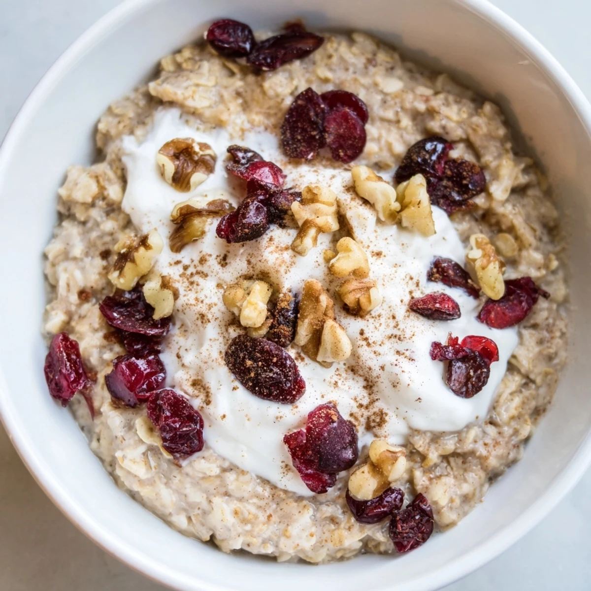 A close-up of a warm bowl of creamy Cranberry Chai Oats, garnished with vibrant cranberries.