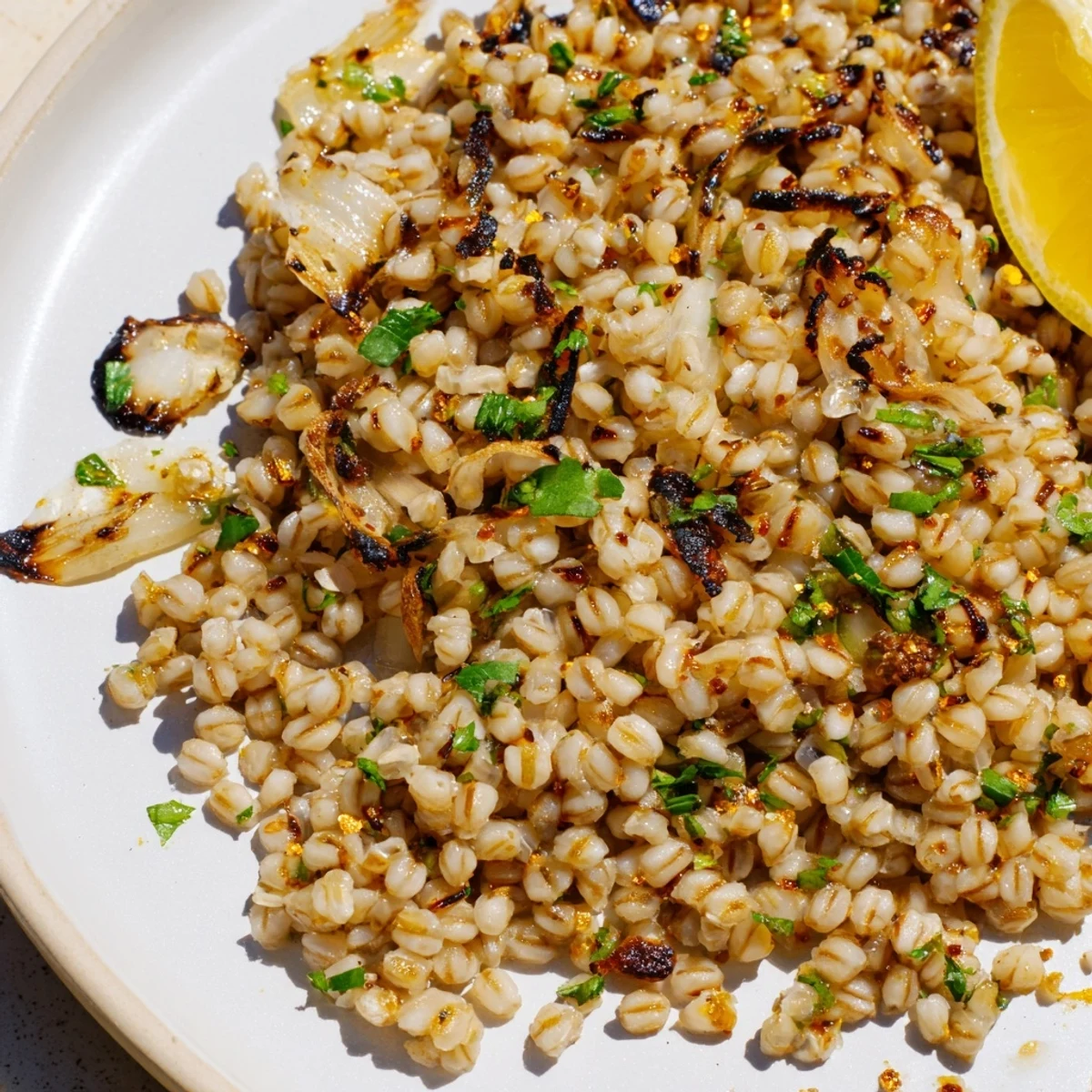 Warm, appetizing serving: flavorful charred barley, finished with fresh parsley and a lemon wedge.