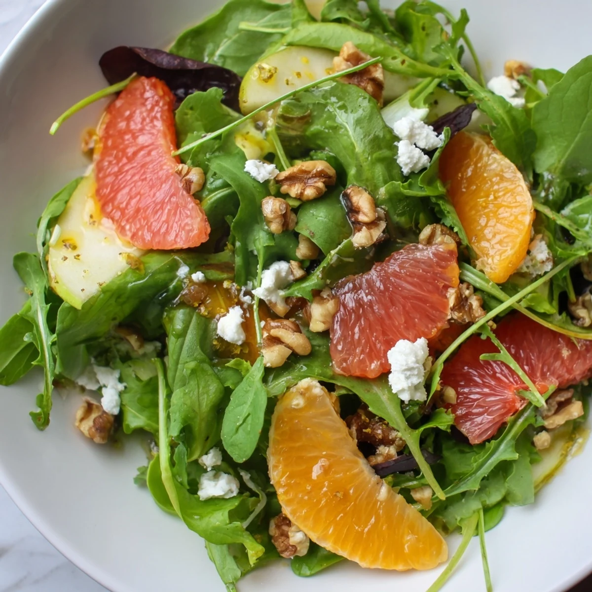 Fresh Citrus Pear Greens salad, a colorful mix of fruit and greens drizzled with vinaigrette.