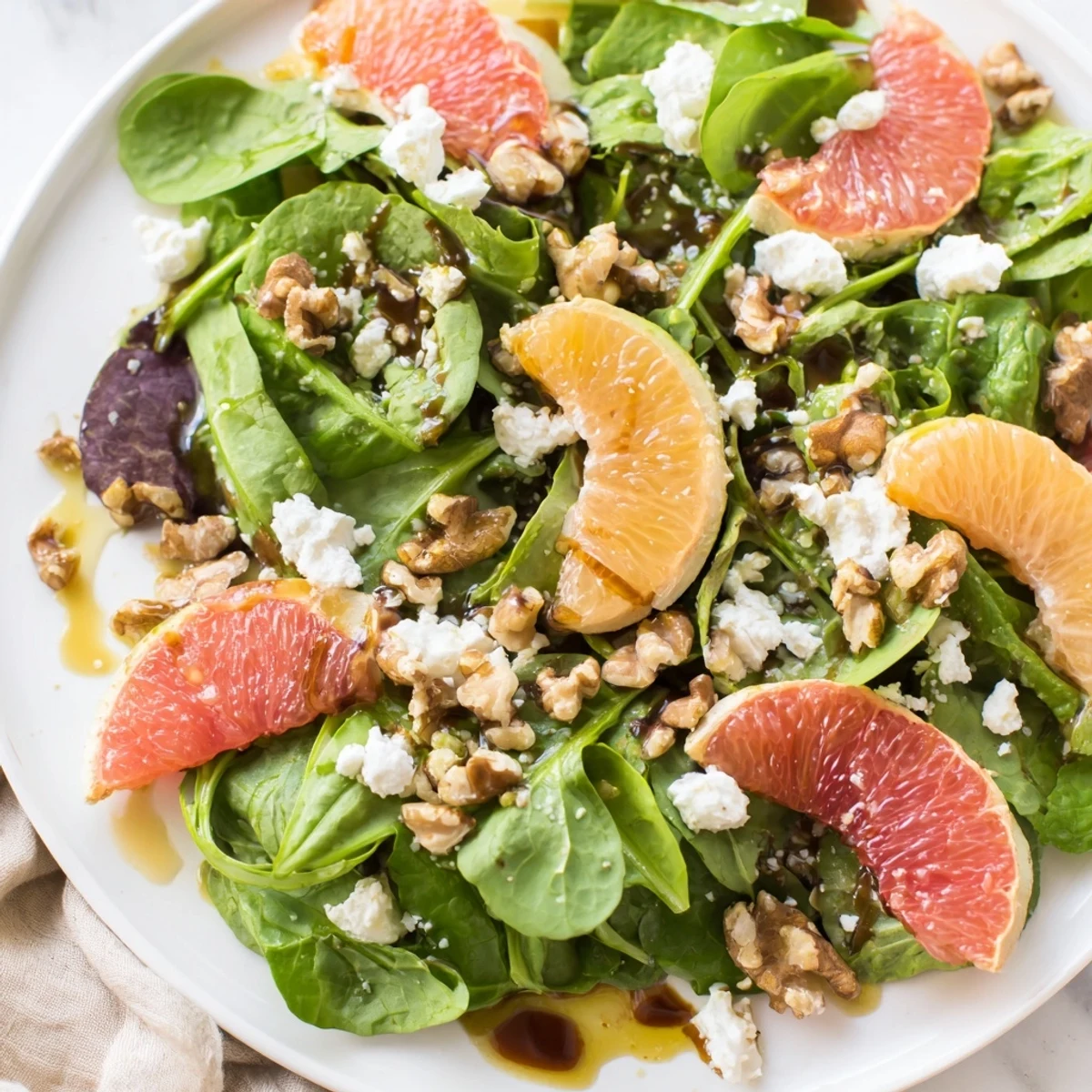 Bright and healthy Citrus Pear Greens salad featuring sliced pears and citrus fruit with crumbled cheese.