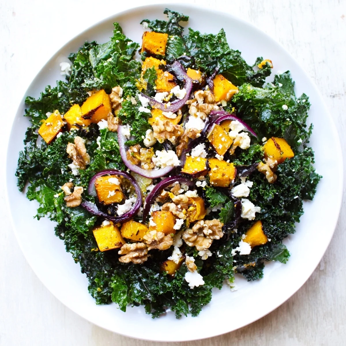 A colorful Winter Kale Salad with roasted squash, featuring golden squash and crumbled feta.