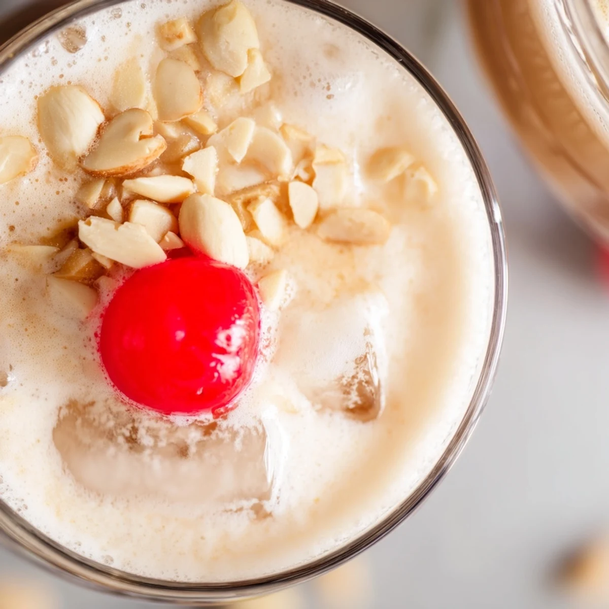 Rich Frosted Toasted Almond cocktail in a glass with ice, almonds, and a cherry, ready to sip.