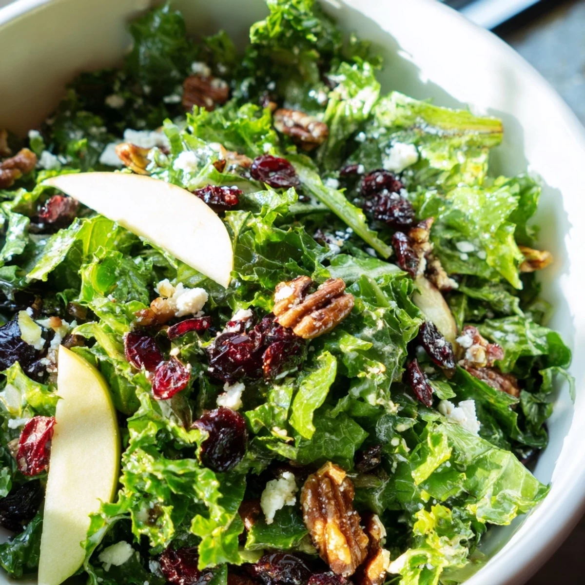 A close-up of Cranberry Winter Greens with crumbled goat cheese and a zesty orange vinaigrette drizzled over the top.
