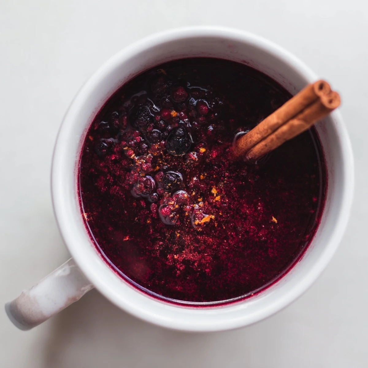 Cozy Berry Blend being poured from a teapot into a white ceramic mug, steam rising from the antioxidant-rich berry drink.