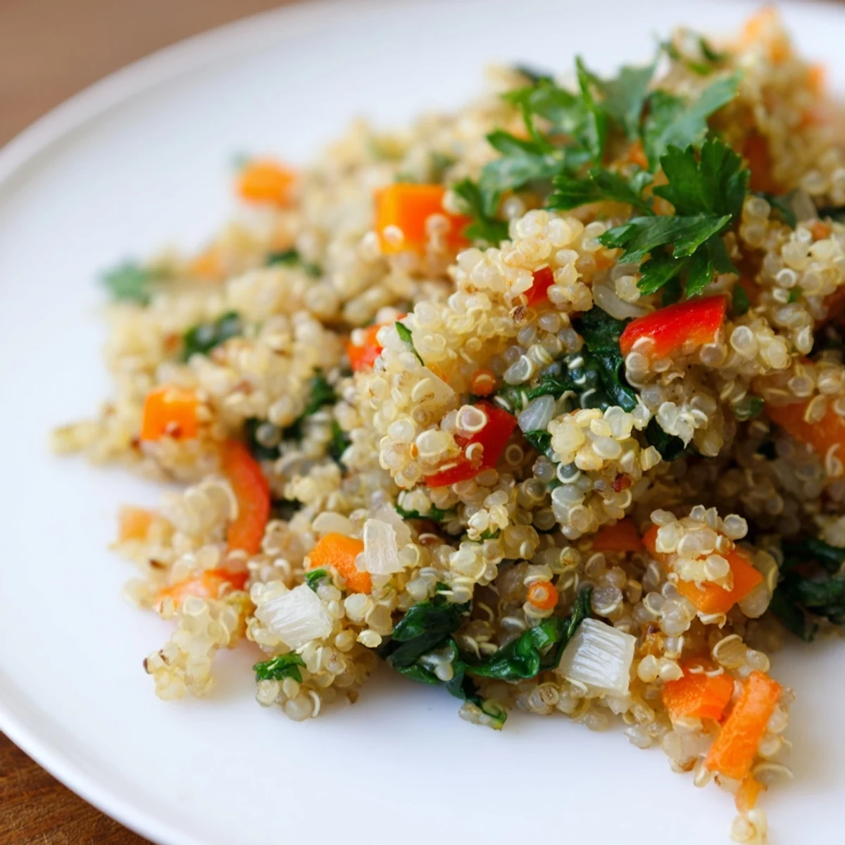 Bright green spinach and diced red bell peppers mixed into warm Savory Quinoa, garnished with fresh parsley.