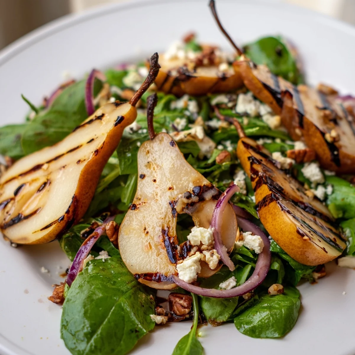 Vibrant mixed greens topped with warm, caramelized pears, feta crumbles, and toasted pecans, ready to serve.