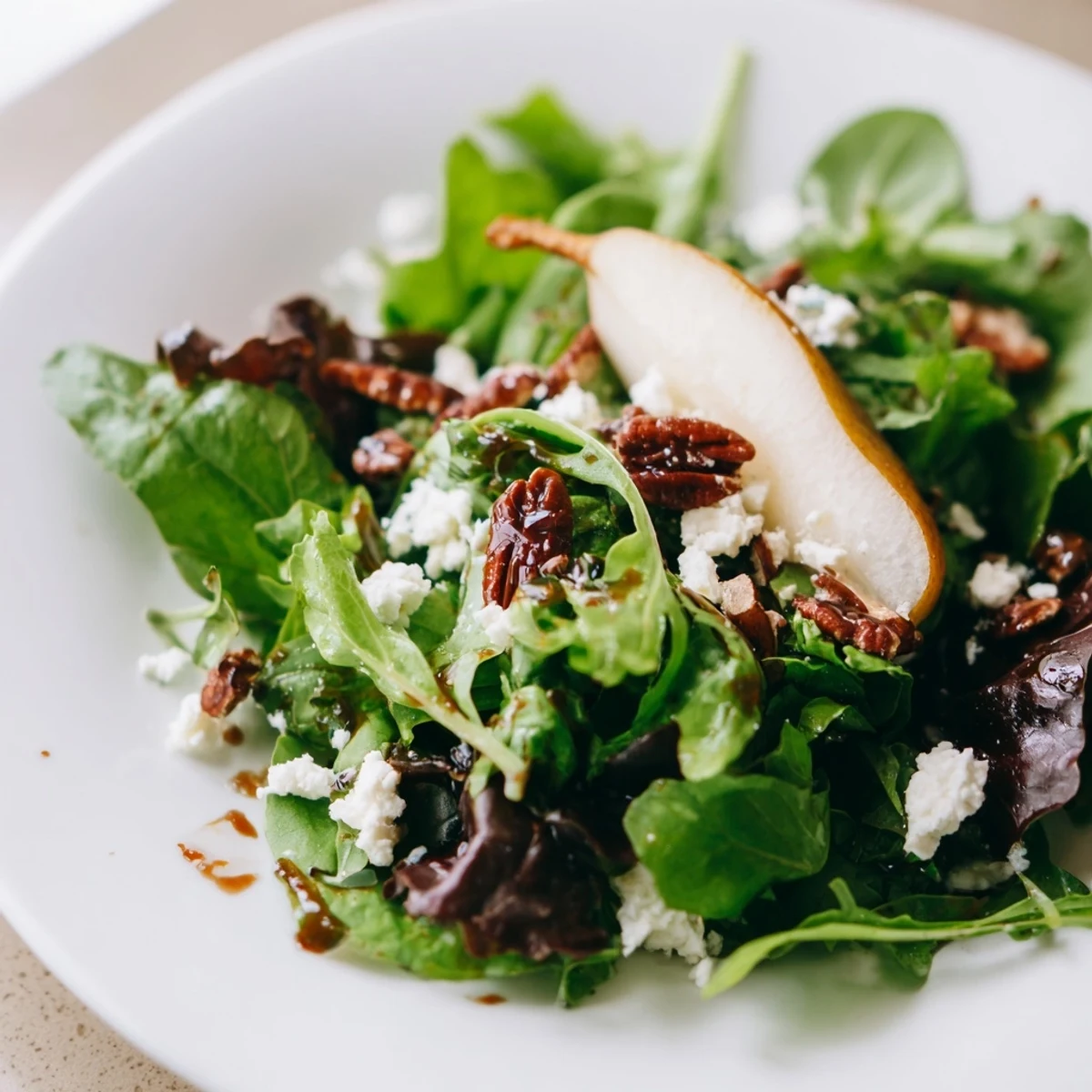 Vibrant Harvest Pear Greens salad with crisp mixed greens, sweet pear slices, and crumbled goat cheese on a rustic plate.