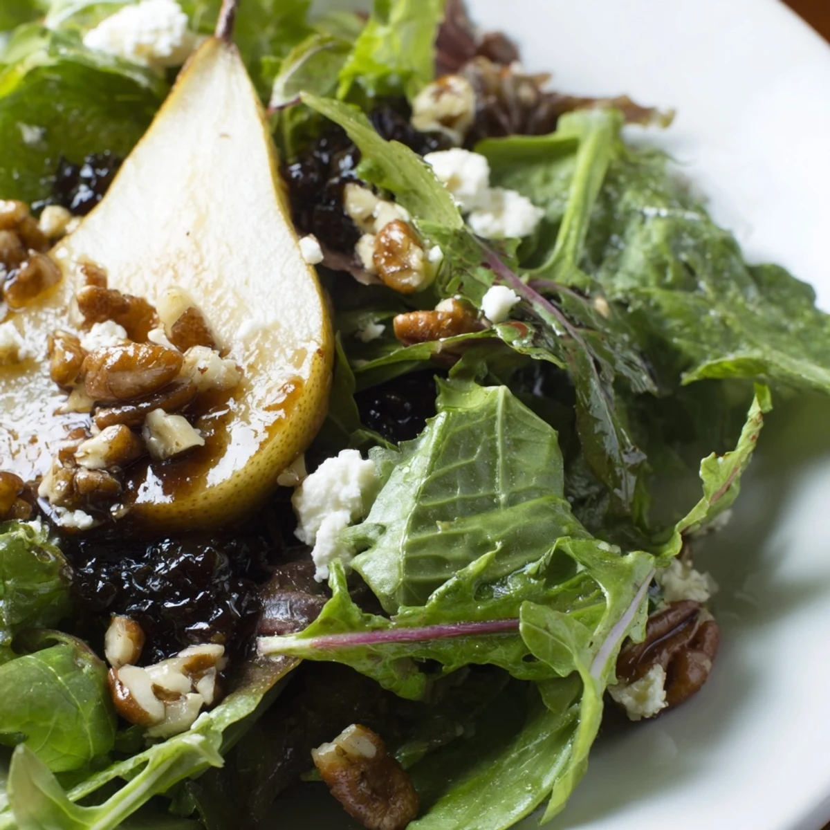 Freshly tossed Harvest Pear Greens salad featuring ripe pears, candied pecans, and greens drizzled with zesty balsamic dressing.