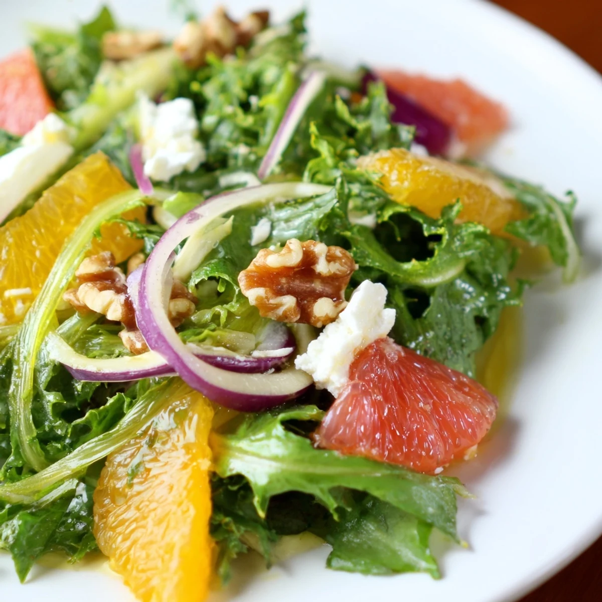 Bright and refreshing Winter Citrus Greens salad served in a wooden bowl, perfect for a healthy, easy vegetarian side dish.