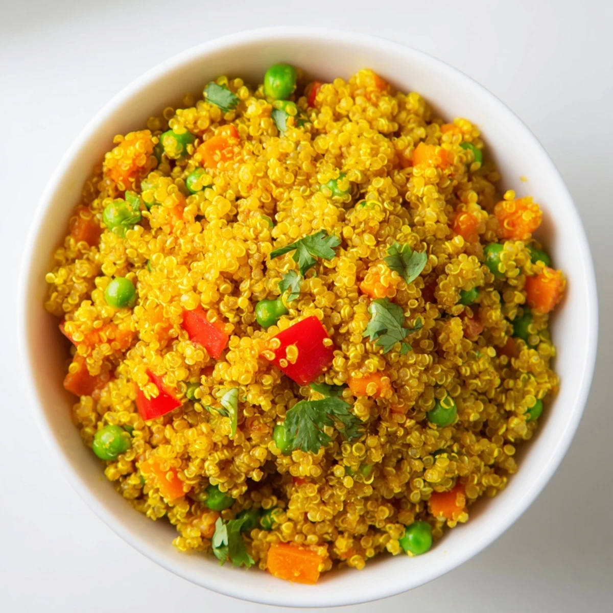 A close-up of Ginger Savory Grain with fluffy quinoa, vibrant diced vegetables, and fresh cilantro garnish, served in a white bowl.