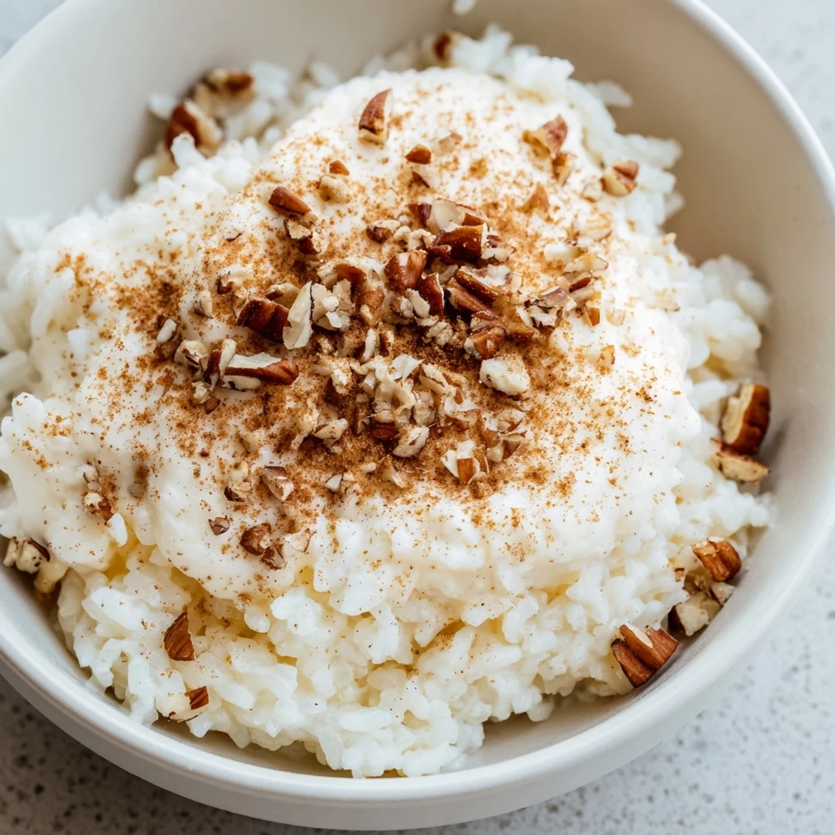 Savory-sweet Frosted Warm Rice served in a bowl, featuring a smooth vanilla glaze and a dusting of cinnamon.