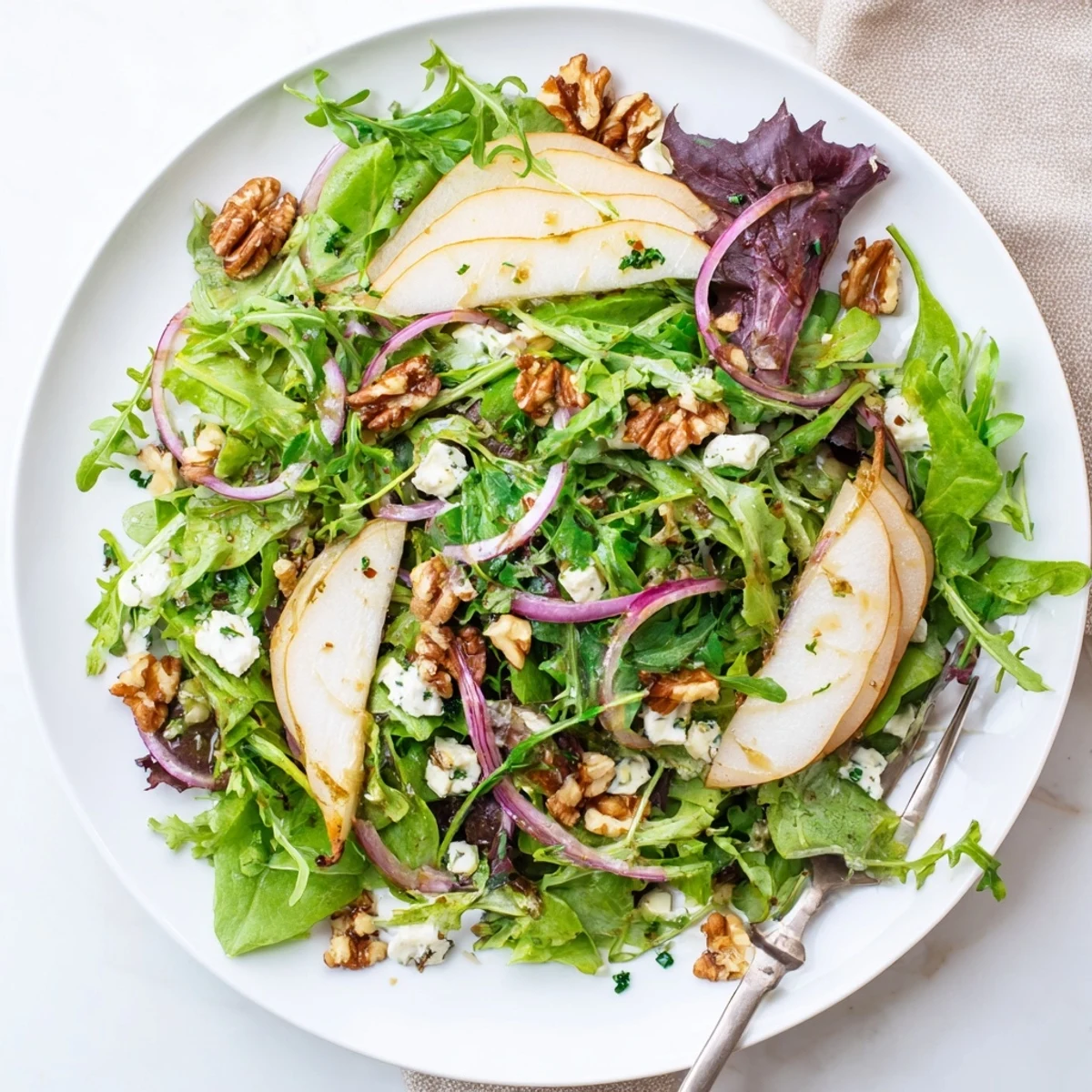 A vibrant Savory Pear Greens salad with peppery arugula, sweet sliced pears, and toasted walnuts on a wooden board.