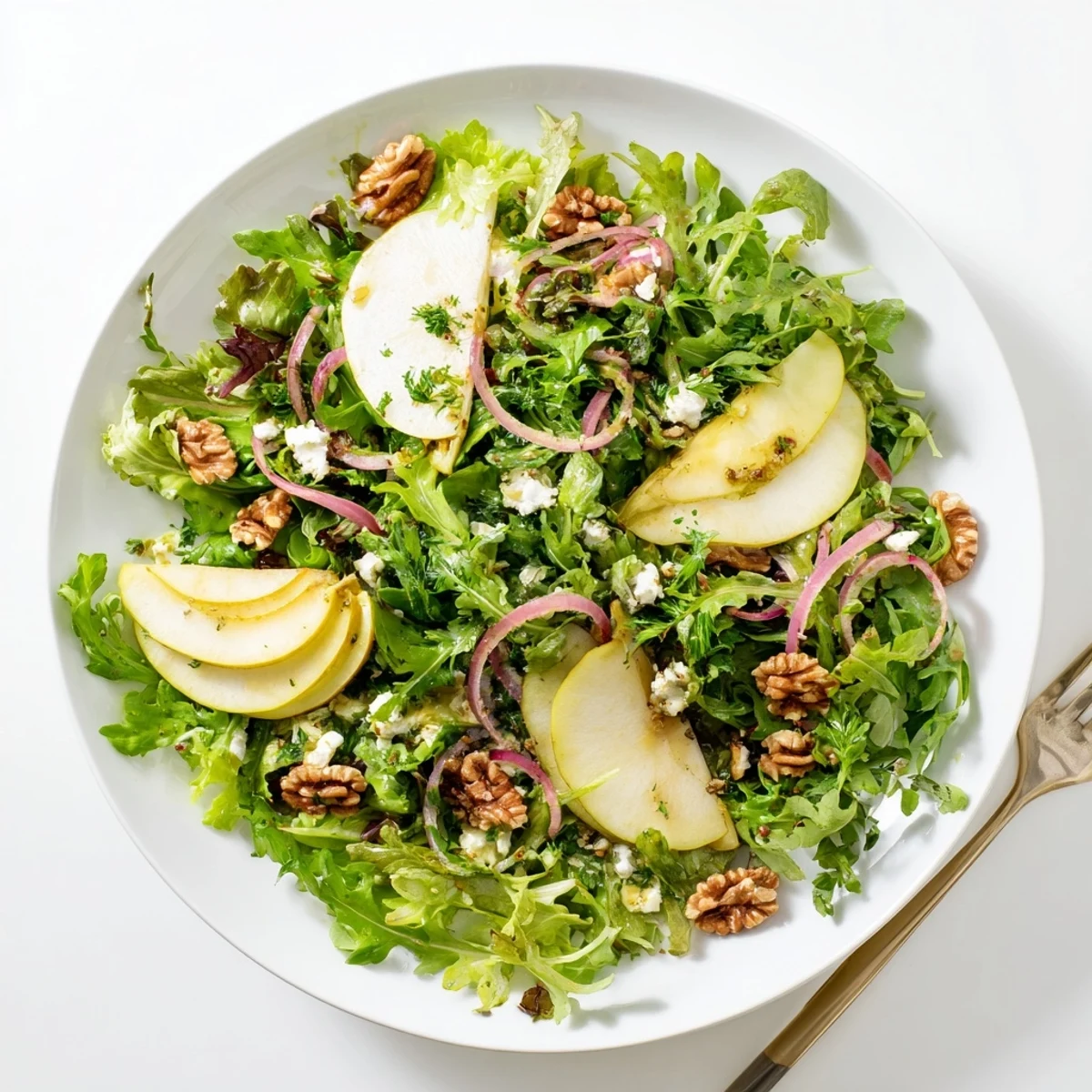 Tossed Savory Pear Greens salad features ripe pears, red onion, and crumbled goat cheese with a light vinaigrette.
