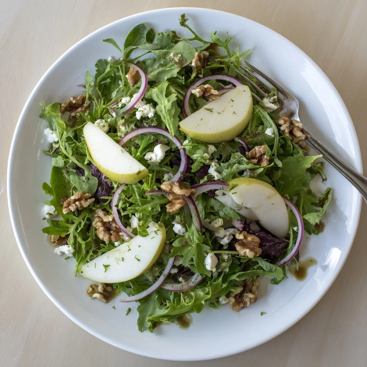 Fresh Savory Pear Greens salad served in a bowl with mixed greens, parsley, and glistening balsamic dressing.