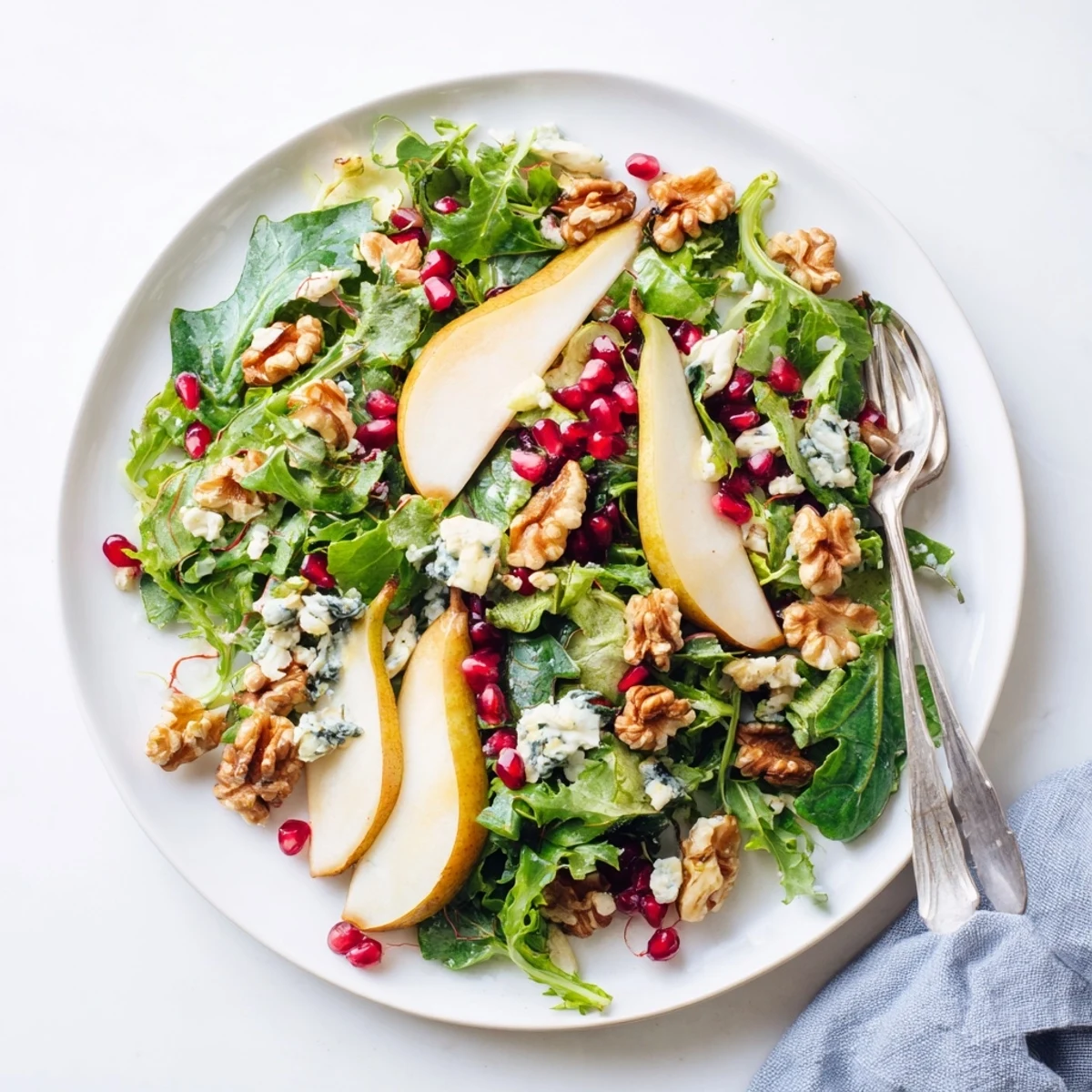 Bright and refreshing Pear Winter Greens salad with sliced pears, crunchy pecans, and goat cheese, served in a rustic white bowl for a healthy lunch.