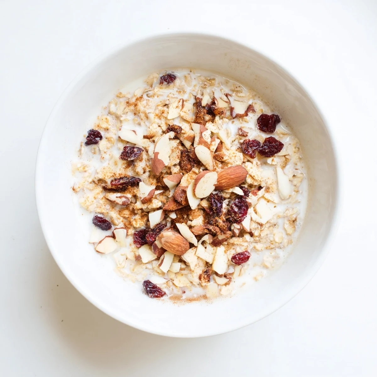 Steaming bowl of creamy Winter Chai Oat topped with toasted nuts and dried cranberries for a cozy morning meal.  