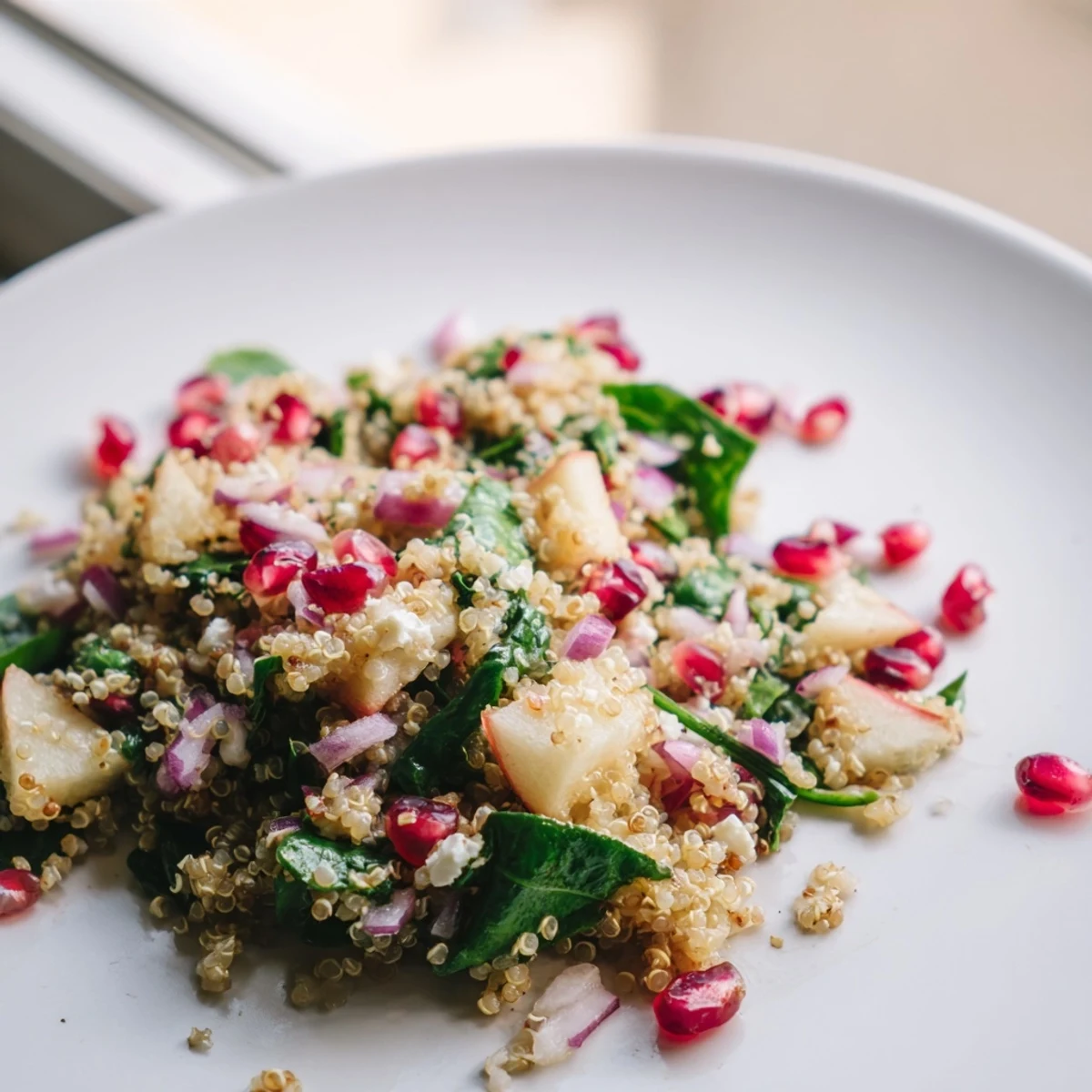 A bowl of Pear Quinoa salad with baby spinach, red onion, and crumbled feta, garnished with toasted pecans.