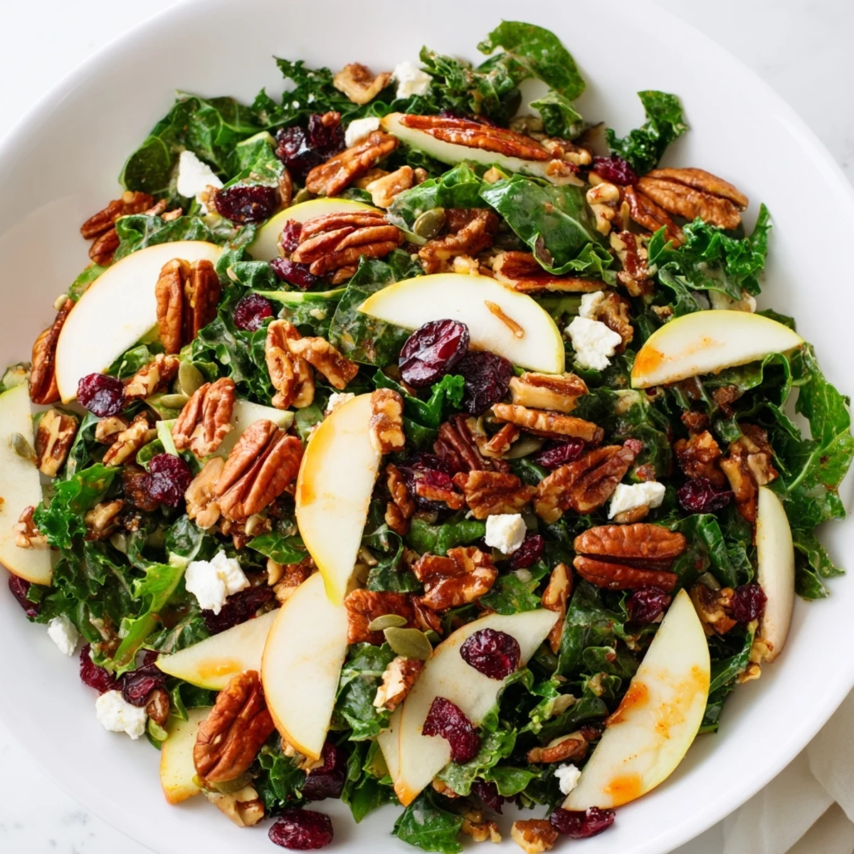 A vibrant bowl of Harvest Winter Greens salad with kale, Swiss chard, and toasted walnuts tossed in a bright citrus vinaigrette.