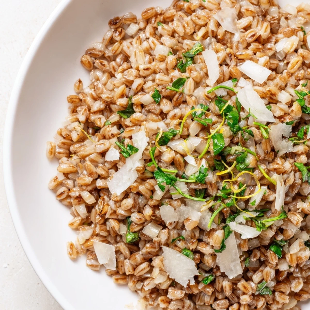 Fluffy Toasty Farro in a shallow bowl, garnished with herbs and a drizzle of olive oil for added flavor.