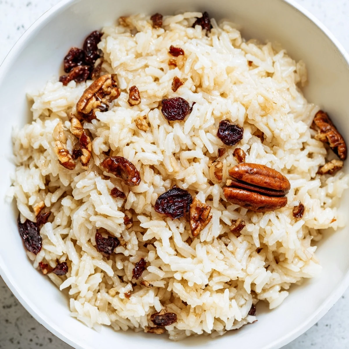 Steam rises gently from the Maple Warm Rice as it sits on a rustic wooden table next to a cinnamon shaker. A spoonful shows creamy texture and melted butter for a delicious breakfast or dessert.