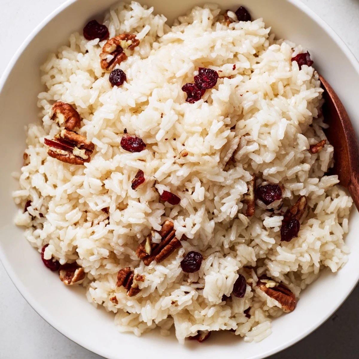A side view of Maple Warm Rice served in a ceramic dish, garnished with chopped walnuts and a dusting of cinnamon. The warm, inviting scene highlights the sweet aroma and soft, fluffy texture.