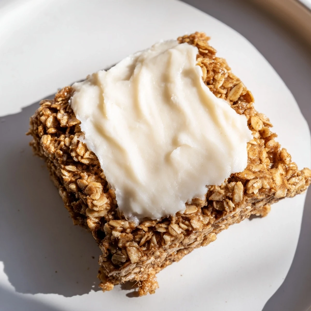A warm slice of Frosted Chai Oat breakfast bake with creamy vanilla frosting and a sprinkle of cinnamon.