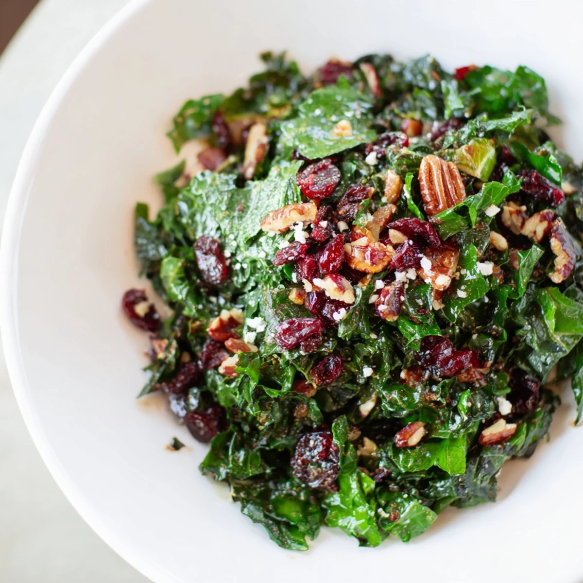 Warm winter salad with wilted spinach, toasted walnuts, and dried cranberries served in a bowl.