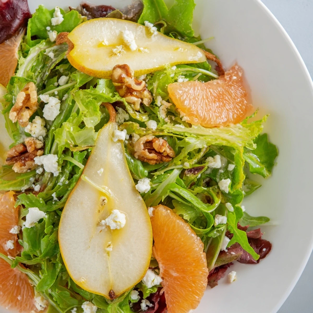 Bright orange and grapefruit segments mingle with thin pear slices over arugula and spinach, garnished with toasted walnuts and a light honey Dijon dressing.