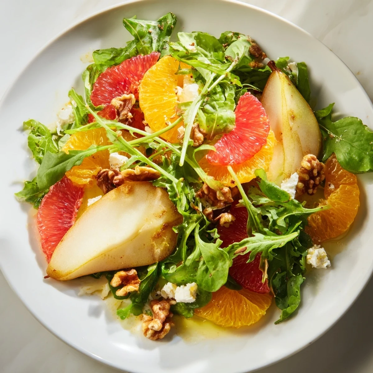 A close-up view of the Pear Citrus Greens salad shows juicy fruit, fresh greens, and crumbled feta, ready to serve as a healthy vegetarian side.