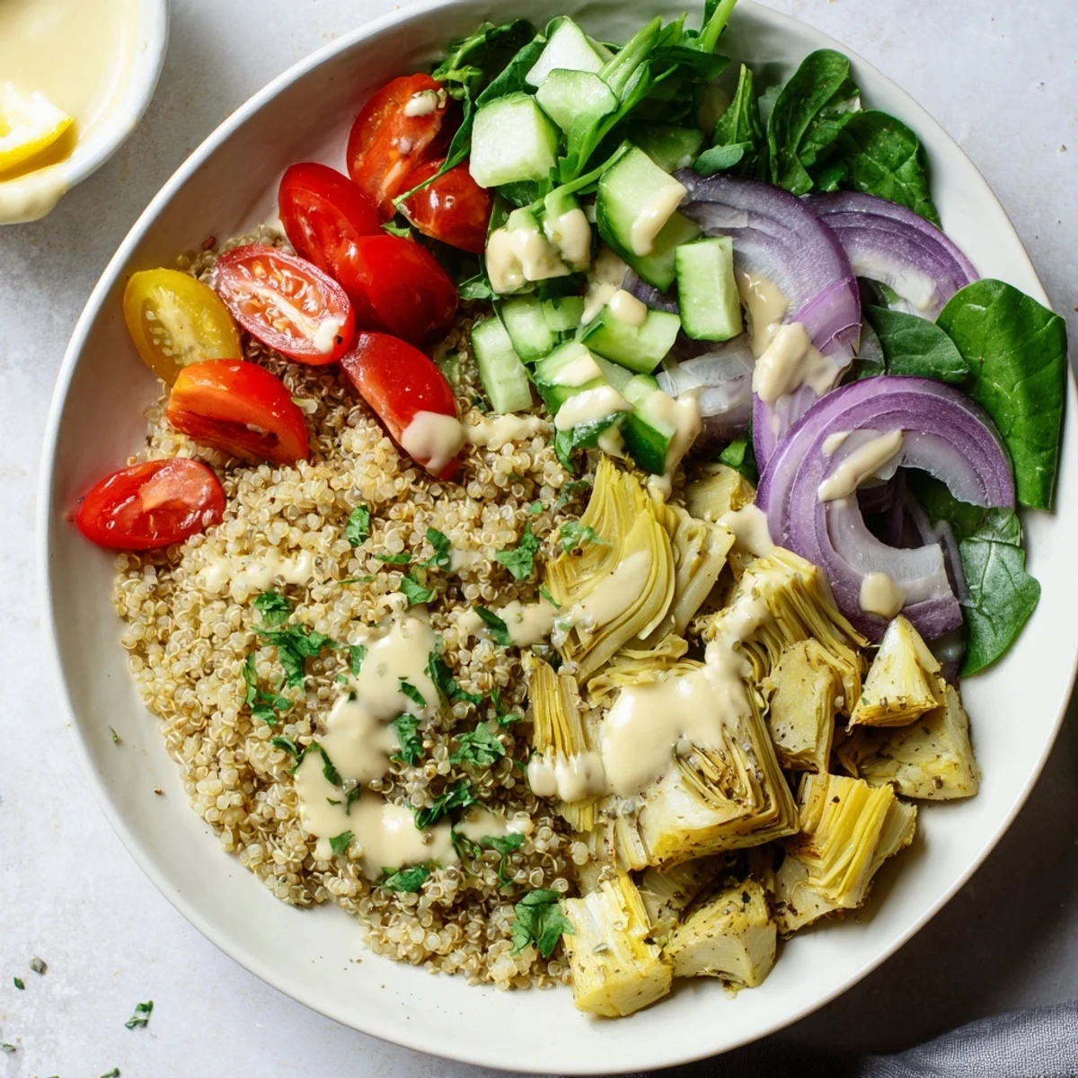 Golden-brown crispy roasted artichokes topped on a vibrant Lemon Tahini Quinoa Grain Bowl, garnished with fresh parsley.