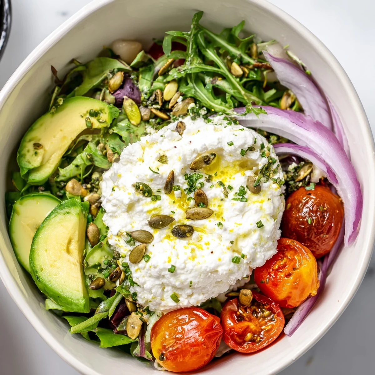 Creamy Cottage Cheese and Roasted Tomato Salad Bowl with roasted tomatoes and avocado slices on mixed greens.