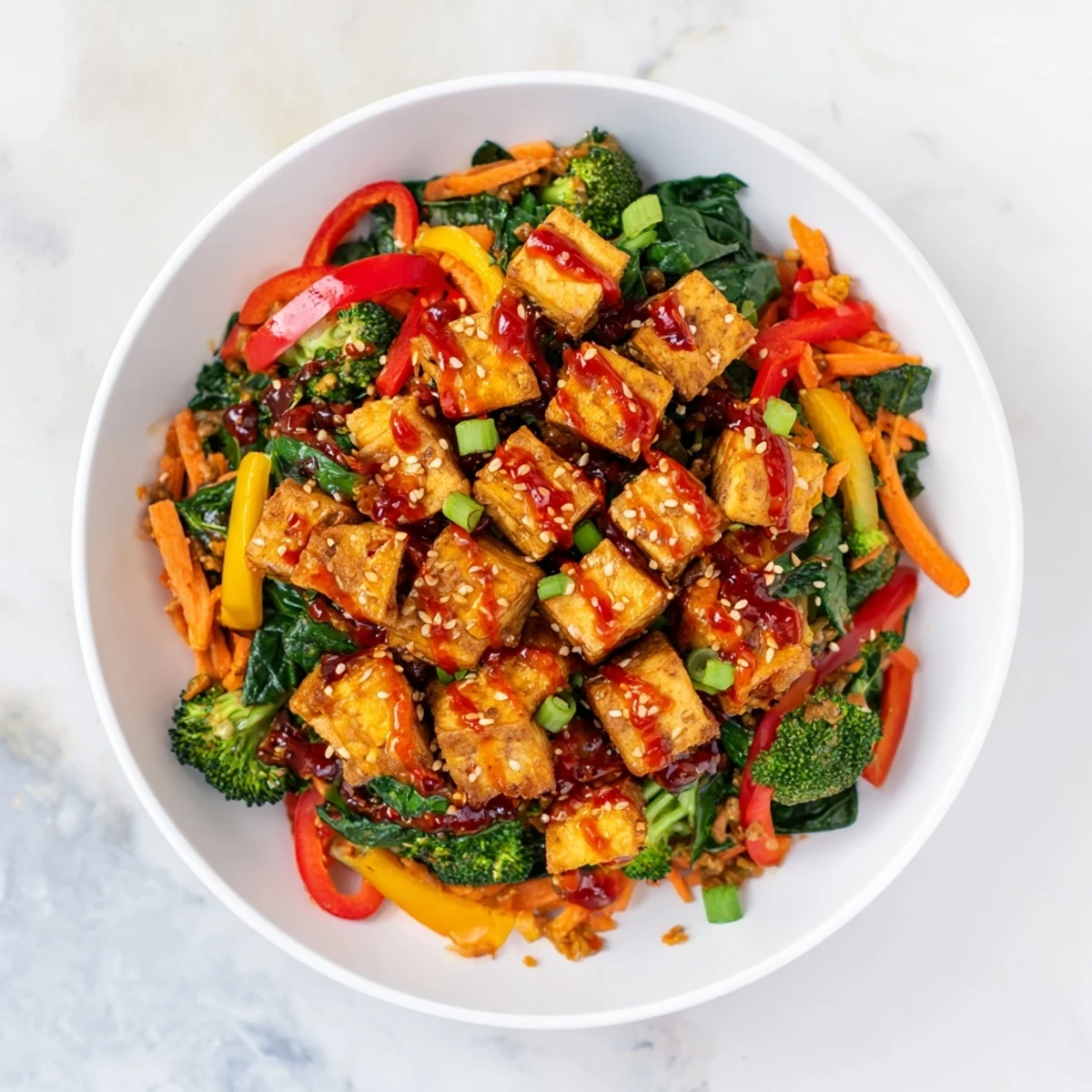 Dinner is served: golden pan-fried tofu tossed in chili crisp sauce, alongside bright greens and crunchy vegetables on a bed of brown rice.