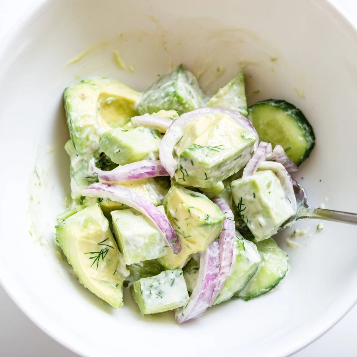 This Creamy Avocado Cucumber Salad Bowl with Fresh Dill is topped with juicy tomatoes and fresh dill sprigs.