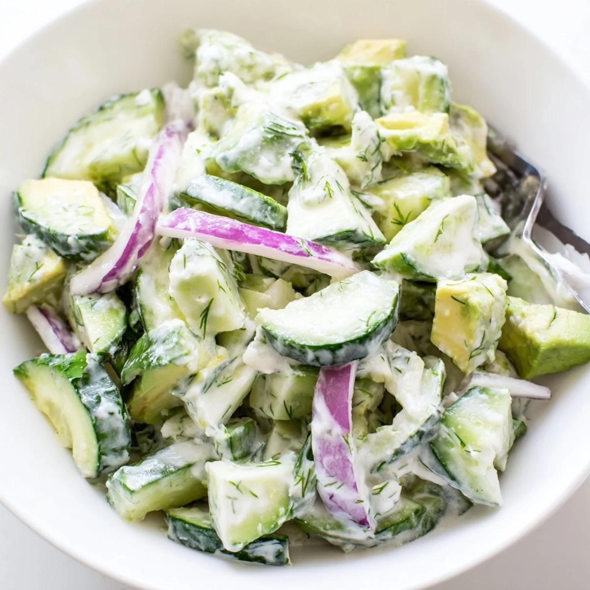 Creamy avocado and crisp cucumber slices are tossed in a tangy yogurt dressing for a refreshing summer side dish.