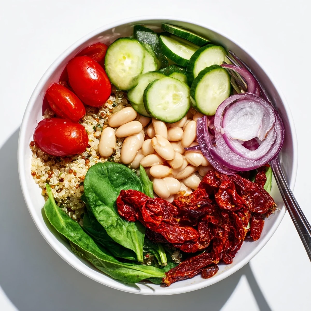 A vibrant Sun-Dried Tomato and White Bean Vegan Bowl with creamy beans and spinach on a bed of fluffy quinoa.