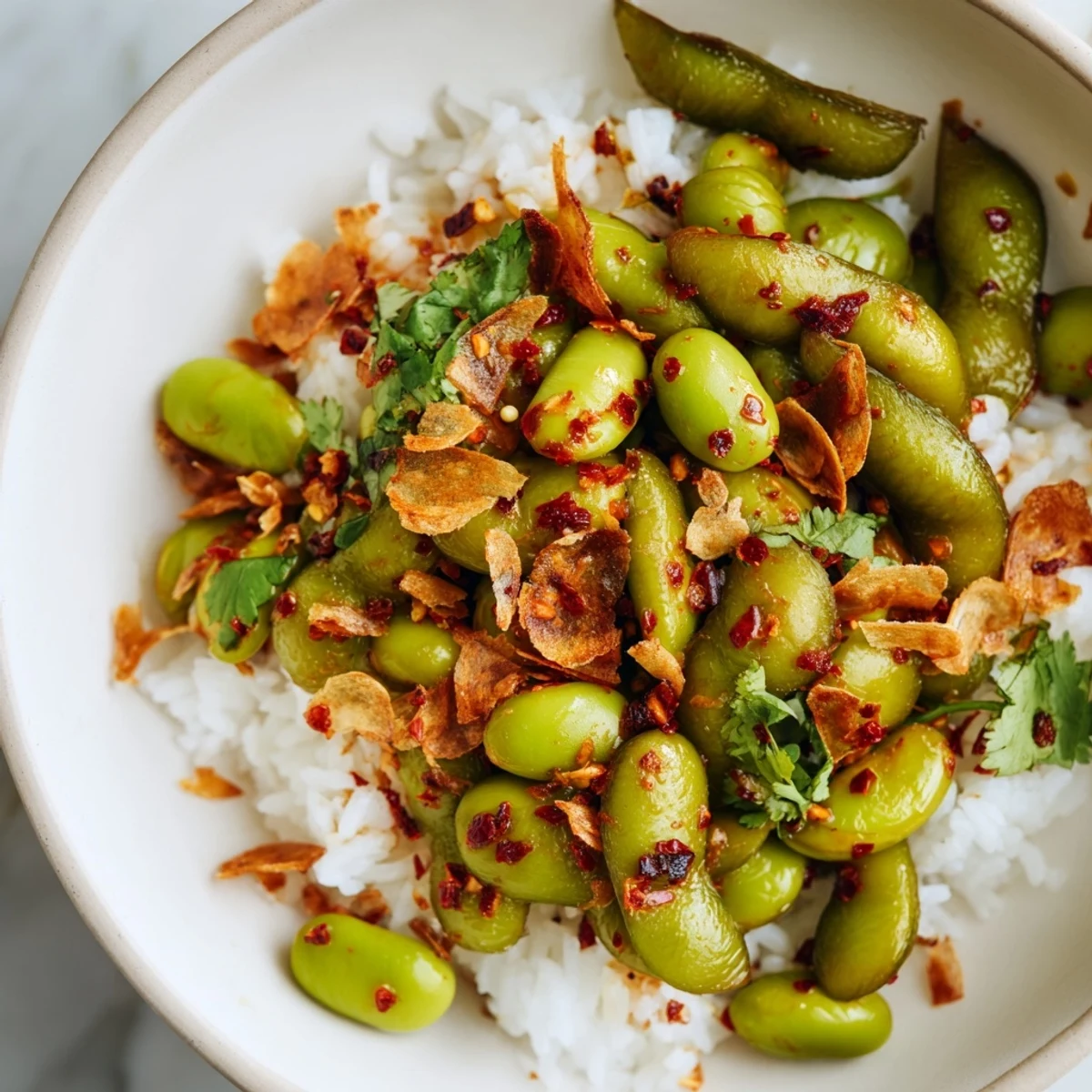 Spicy Chili Oil Edamame Veggie Bowl with Crispy Garlic served fresh with rice and sliced avocado.