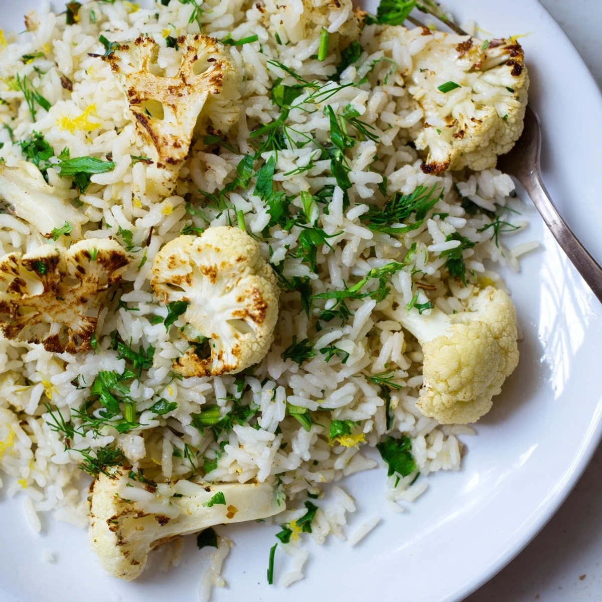 A close-up photo of lemon herb basmati rice with roasted cauliflower highlights the aromatic herbs.