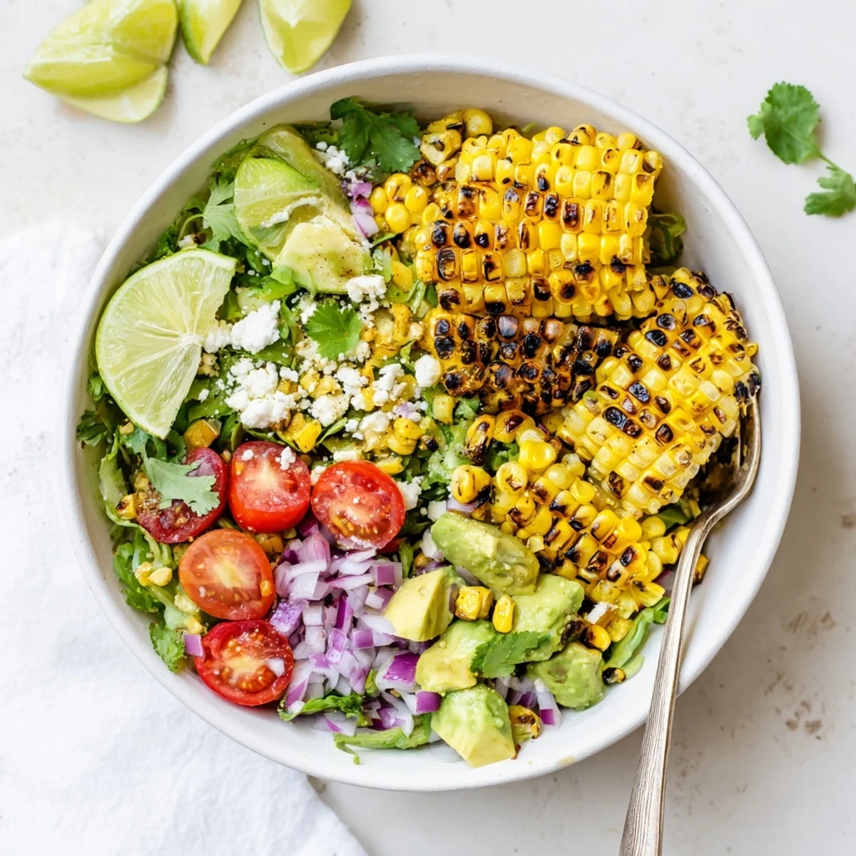 Freshly grilled corn kernels are mixed with creamy avocado, juicy cherry tomatoes, and crumbled cotija cheese in this Charred Corn and Avocado Salad Bowl.