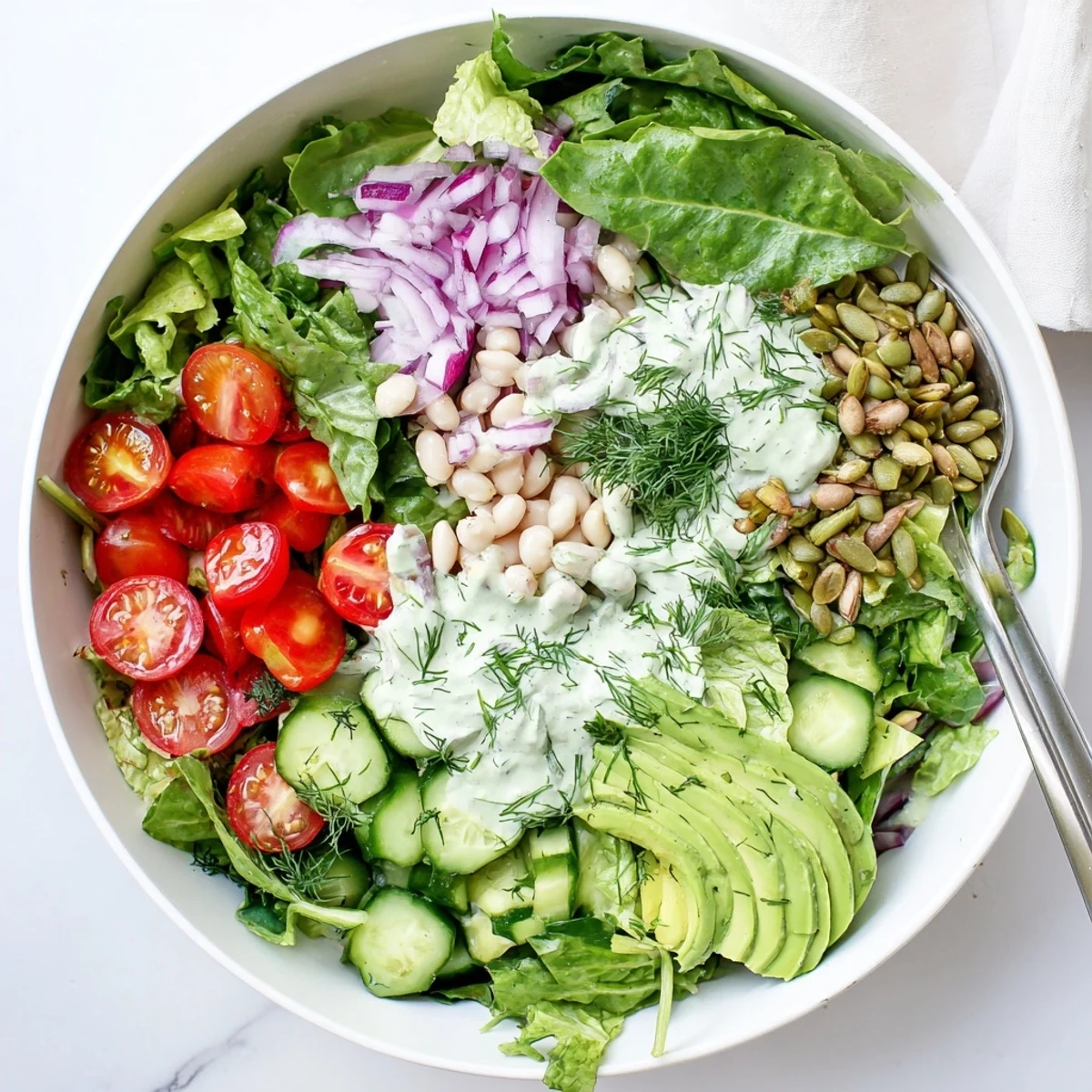 Creamy Dill Pickle Salad Bowl features diced pickles, cherry tomatoes, and cucumber tossed in a tangy dressing, ready to serve.