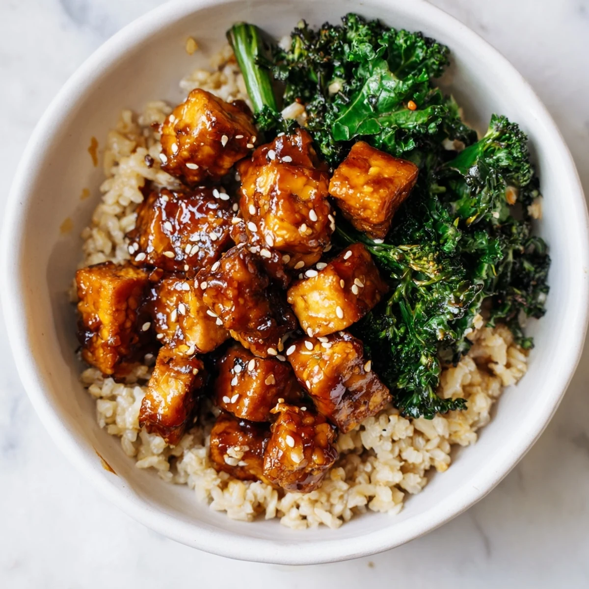 An overhead view of a wholesome vegan bowl with Maple Miso Tempeh, sesame broccoli, carrots, radishes, and fluffy grains ready to serve.