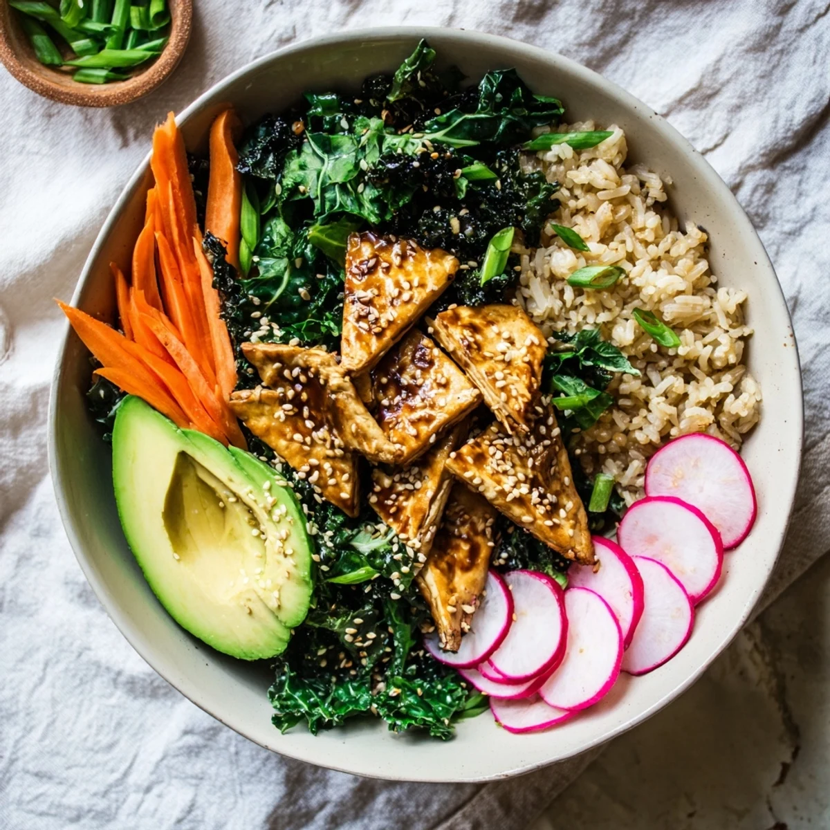 This wholesome Maple Miso Tempeh Vegan Bowl features grains, sautéed kale, spinach, and toasted sesame seeds for garnish.