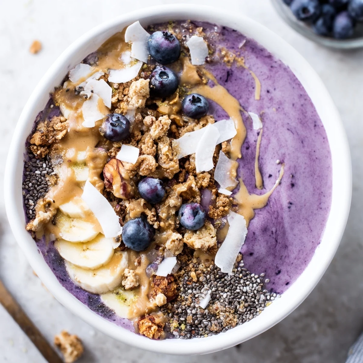 Close-up of a Blueberry Almond Butter Smoothie Bowl with Chia Crunch served in a bowl with blueberries and granola topping.