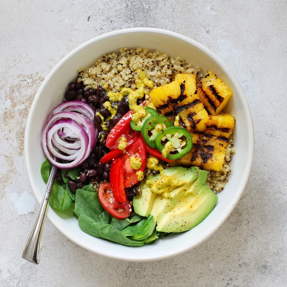 Grilled pineapple chunks and sliced jalapeños top a grain bowl with avocado and cilantro lime dressing in Charred Pineapple Jalapeño Grain Bowl.