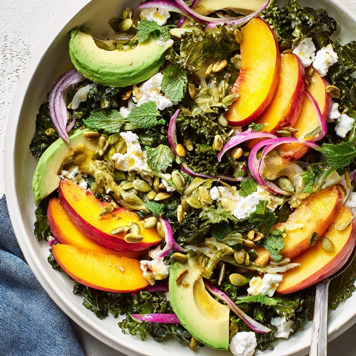 Summer salad featuring tender massaged kale, juicy nectarines, and savory spiced pistachio crumble