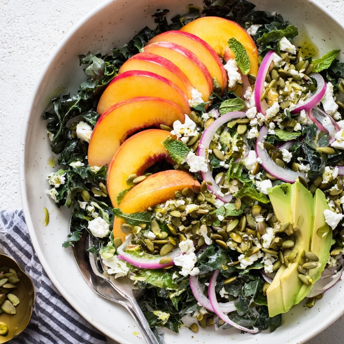 Fresh shaved kale salad with sweet nectarines, creamy avocado, and toasted pistachio topping