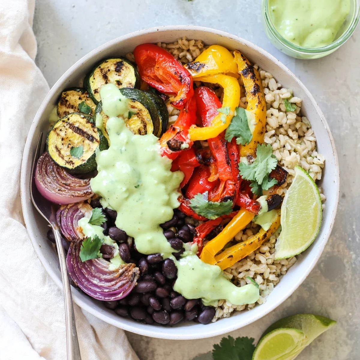 Colorful roasted chili lime zucchini veggie bowl drizzled with creamy avocado crema topping