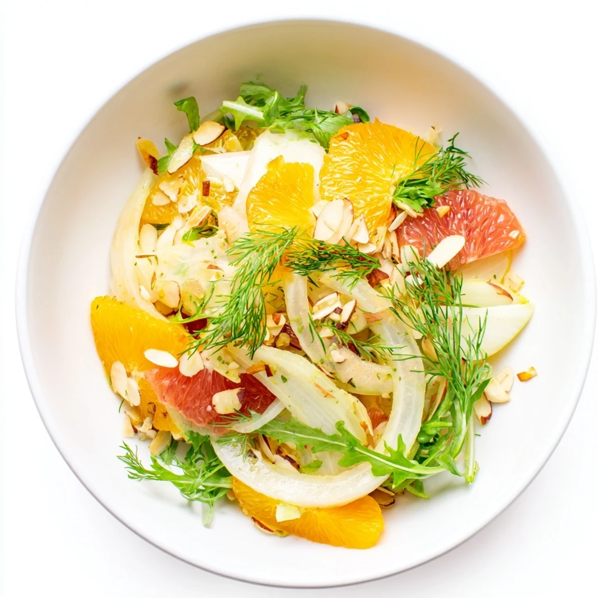 Colorful citrus fennel and arugula salad bowl topped with golden toasted almonds