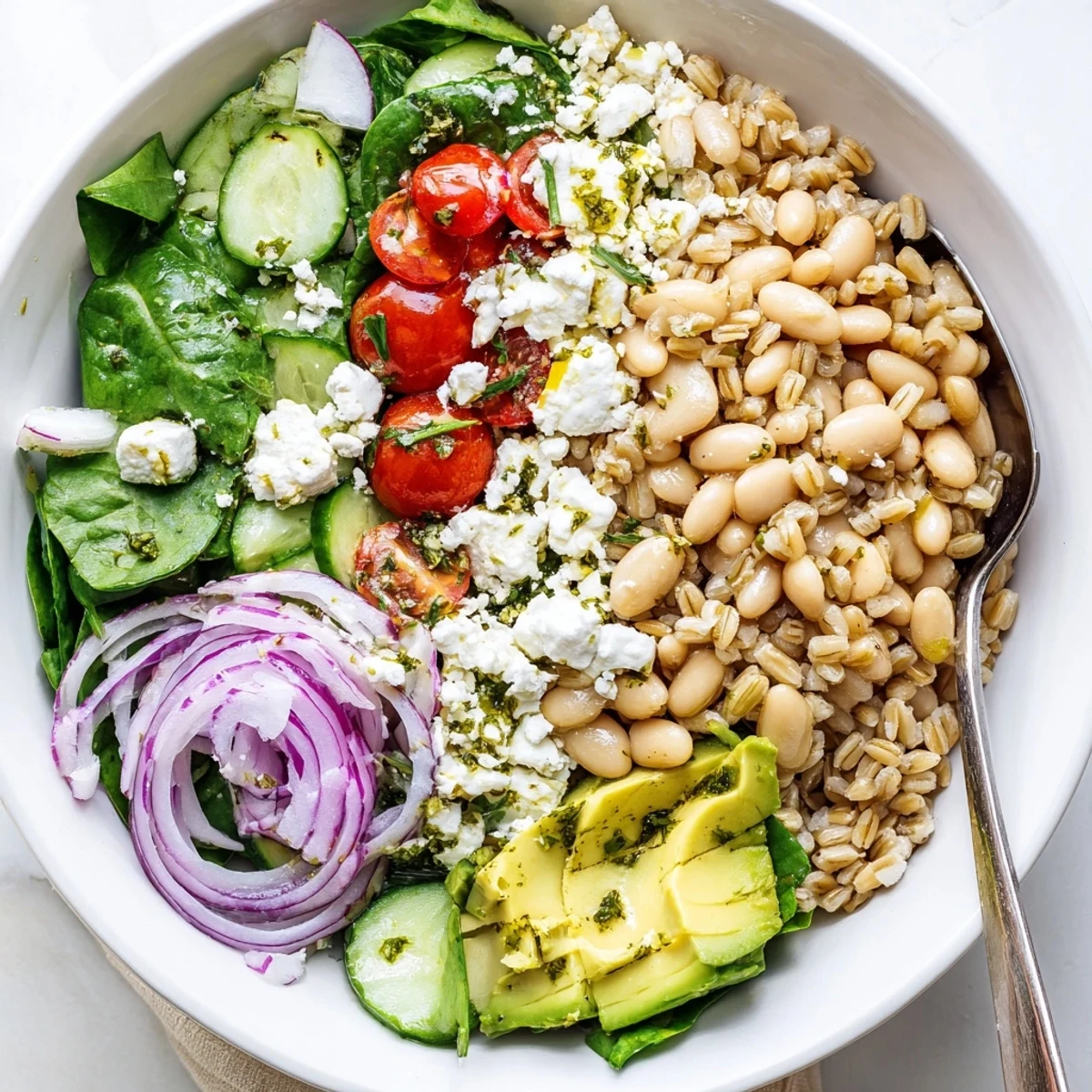 Colorful roasted garlic butter bean grain bowl topped with fresh vegetables and zesty lemon herb dressing
